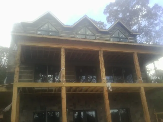 Dormers and porch framing on a large log home under construction — Roof Coating work by our crew in Ringgold