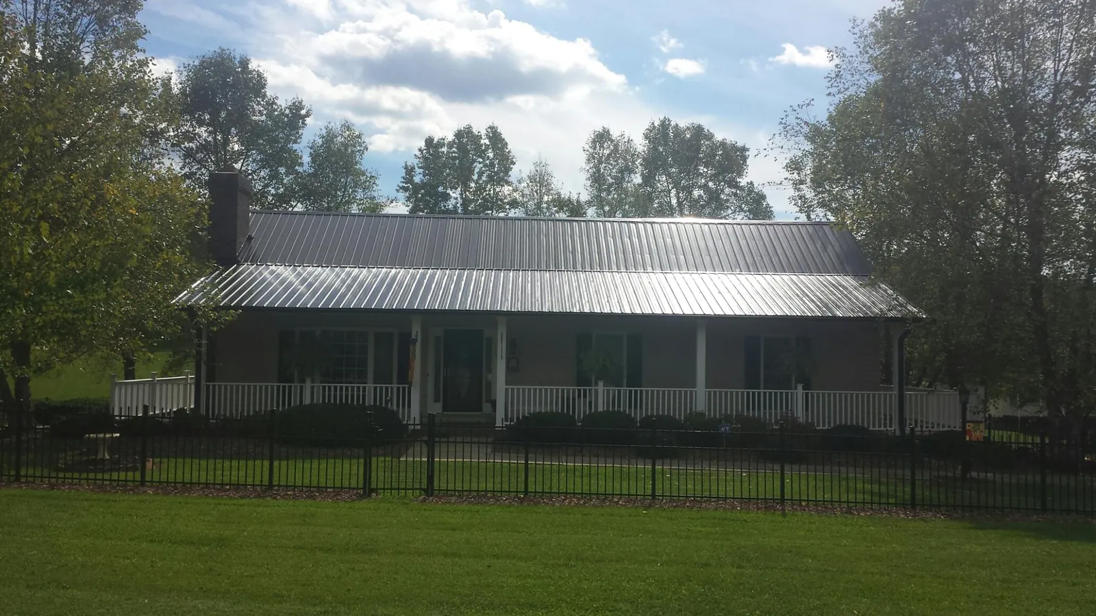 Gray metal roof on a brick ranch with a full width front porch — Gutter Guard Installation work by our crew in Ringgold
