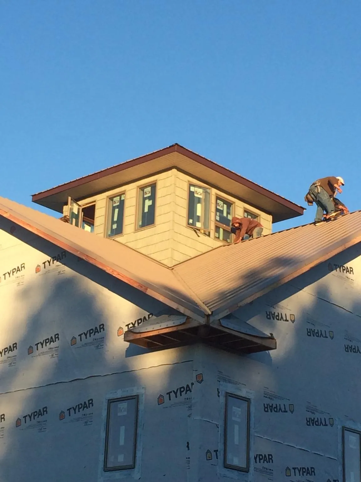 Roofers working around a rooftop cupola on a new metal roof at sunset — Roof Waterproofing in Ringgold by Roofing Brothers